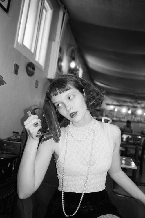 A black-and-white portrait of a young woman in a café